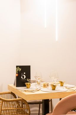 Mesa para dos junto a una pared blanca, con la carta de 5 Sentidos y copas