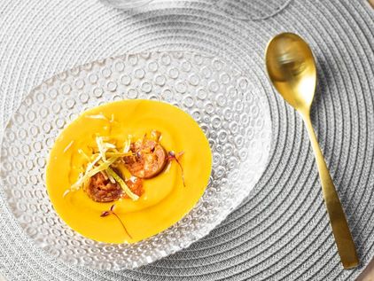 Crema anaranjada con chorizo y tiras crujientes, junto a una cuchara dorada