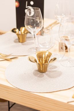 Bajoplato blanco con un portavelas dorado y copas, delante de la carta del restaurante