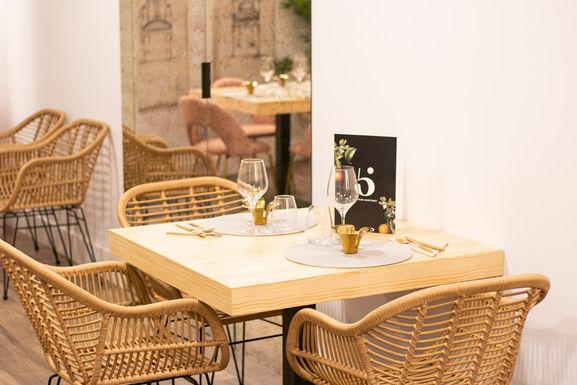 Mesa con sillas de mimbre y la carta, ante los cuadros de sillones del comedor