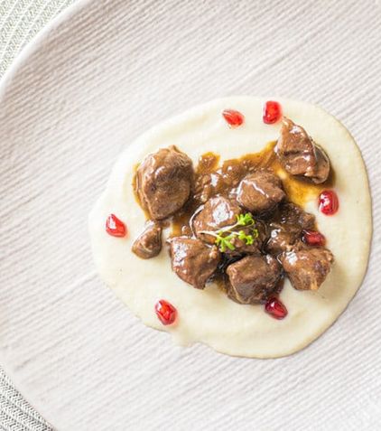 Carne guisada con granada sobre un puré blanco