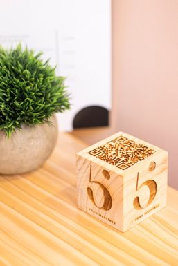 Cubo de madera con el logo de 5 Sentidos junto a una planta