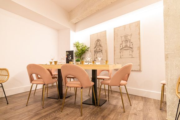 Comedor con mesas de madera, sillas rosas y cuadros de sillones