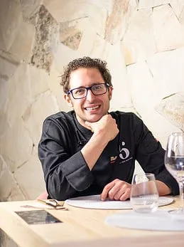 Fran Martínez sonríe sentado a una mesa, con la mano en la barbilla