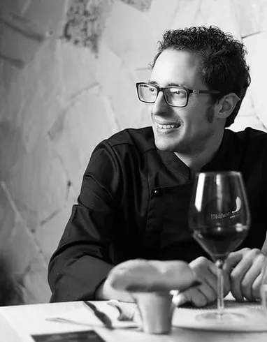 Fran Martínez sonríe sentado a una mesa, con una copa de vino tinto