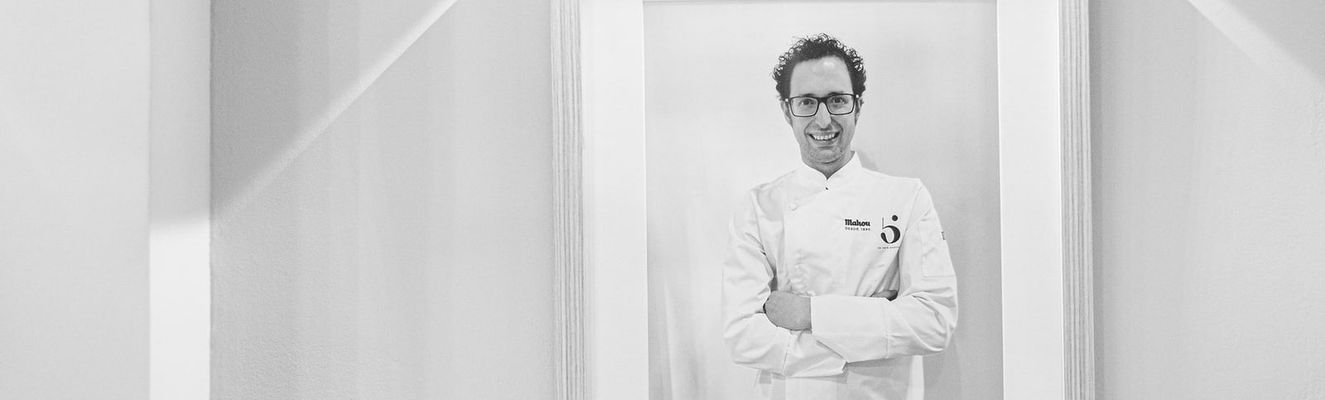 Retrato enmarcado de Fran Martínez con chaquetilla de cocinero, en una pared blanca